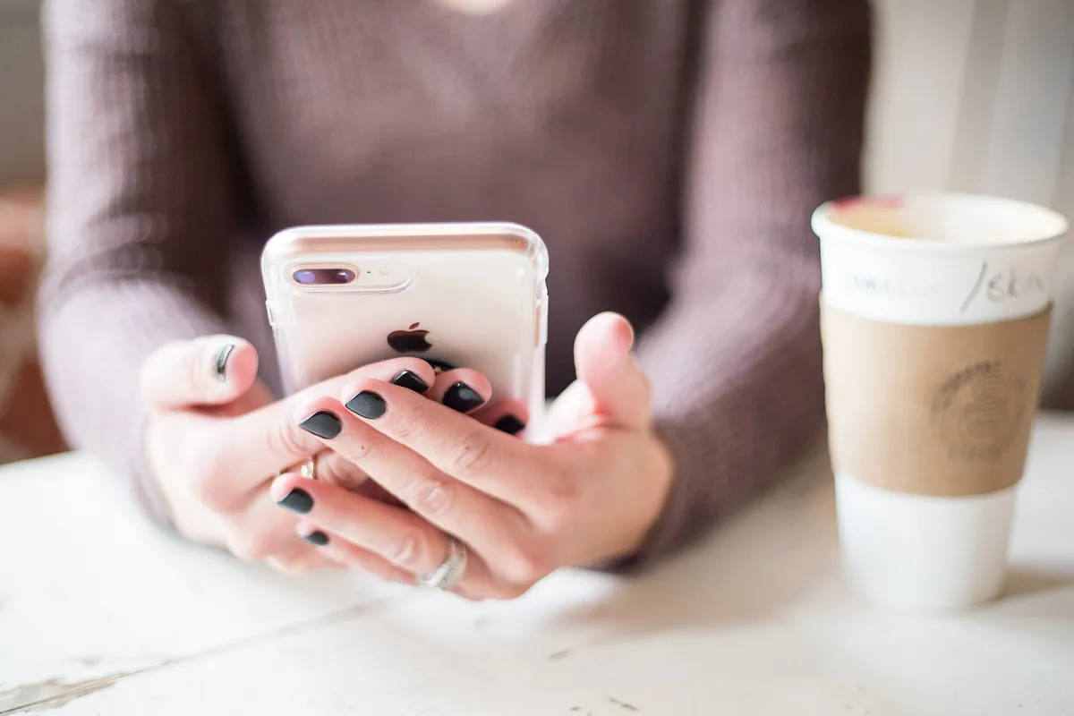 женщина держит iPhone в руках за столом